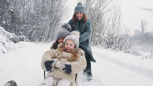 Family sledding in winter winter activity. happy laughing family woman with 2 daughters are enjoying