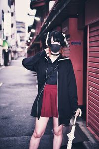 Full length of woman holding umbrella standing in city