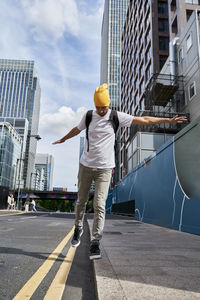 Man with arms outstretched balancing on edge of footpath