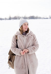 Young girl in beige clothes, fur coat made of artificial fur walks in winter