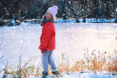 Full length portrait of girl standing on snow covered field during winter