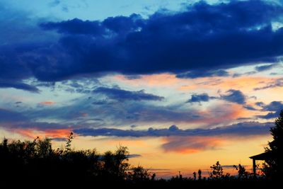 Low angle view of silhouette trees against dramatic sky