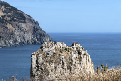 Scenic view of sea and cliff against clear blue sky