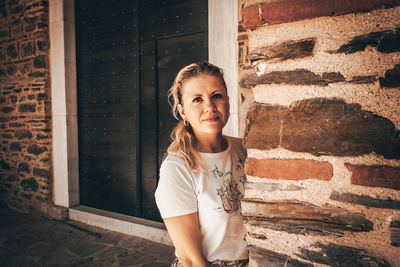 Portrait of teenage girl standing against brick wall