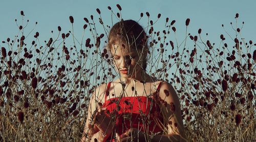 Portrait of young woman standing against sky