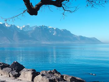 Scenic view of sea and mountains against blue sky