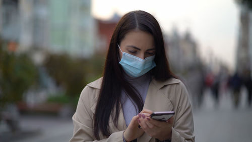 Portrait of young woman using mobile phone in city