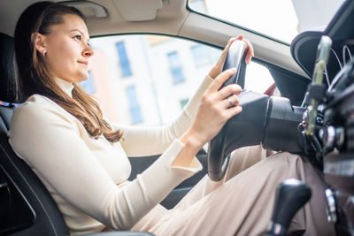 Young woman using phone while sitting in car