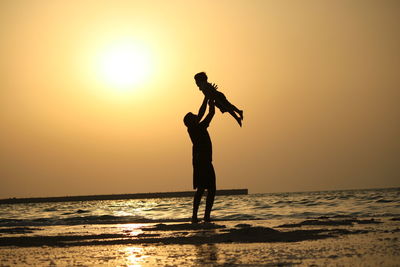 Silhouette man standing at beach during sunset