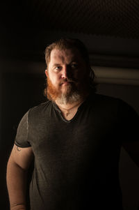 Portrait of young man standing against black background