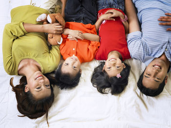 High angle portrait of happy family lying on mattress at home