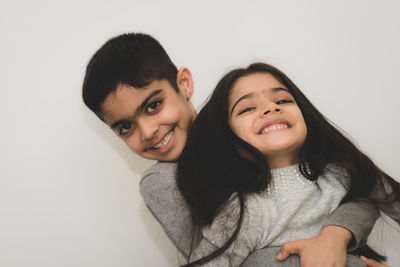 Portrait of smiling siblings standing against white background