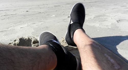Low section of man wearing shoes on beach