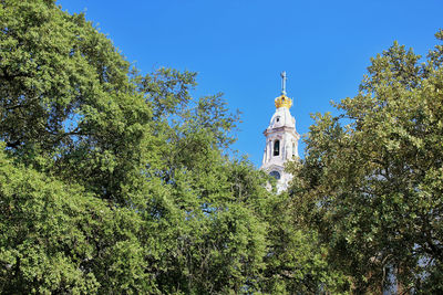 Low angle view of trees and building against sky