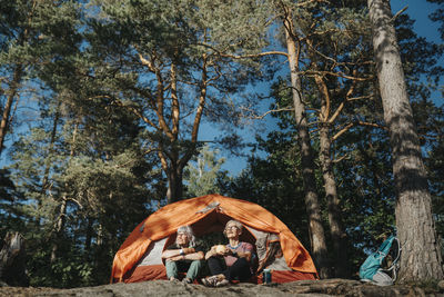 Two senior women sitting in front of tent at campsite