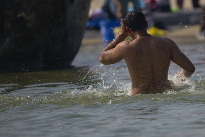 Rear view of shirtless boy in water