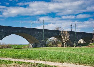 Arch bridge on field against sky