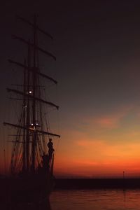 Silhouette of sailboat sailing on sea at sunset