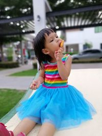 Cute girl eating ice cream while sitting outdoors