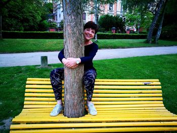 Portrait of smiling young woman sitting on bench in park