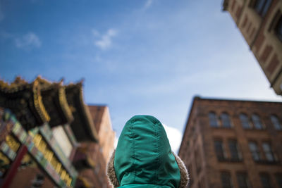 Low angle view of person wearing hooded shirt against buildings