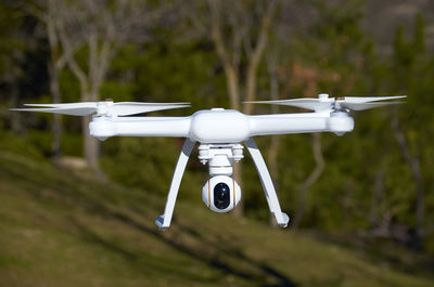 Close-up of quadcopter flying against trees