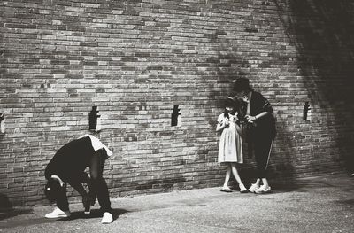 Rear view of people standing against brick wall