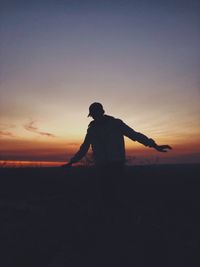 Silhouette man standing on beach against sky during sunset