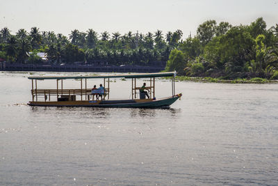 People in boat on river against sky