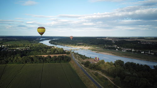 Hot air balloons flying over landscape against sky