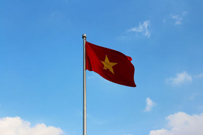 Low angle view of flag against blue sky