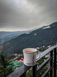 Coffee cup on railing against mountains