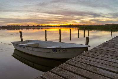 Wooden pier on lake against sky during sunset