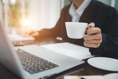 Midsection of woman using laptop on table