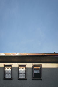 Building from outside with open and closed windows, along with the blue sky.