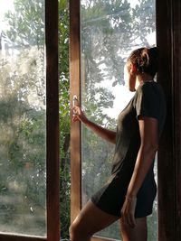 Side view of woman standing by window