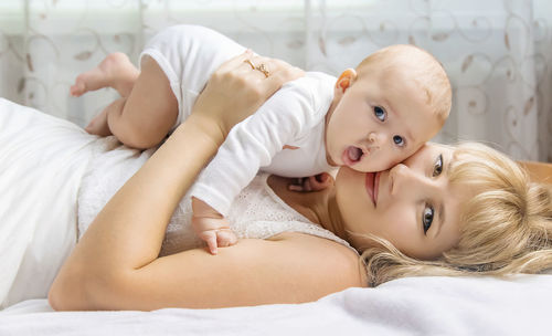 Portrait of mother with daughter lying on bed at home