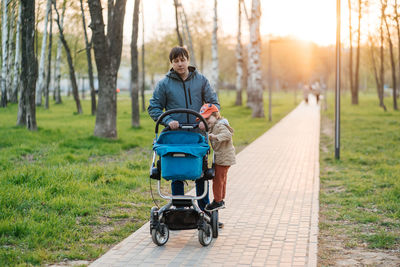 Dad with stroller and toddler son walking in the park