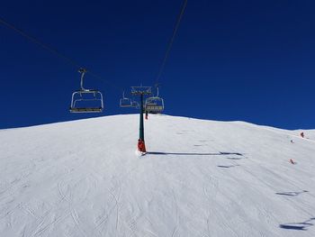 Overhead cable car in snow covered mountains against clear sky