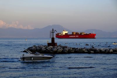 Boat on sea by buildings against sky