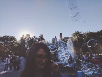 Man and woman holding bubbles in city against clear sky
