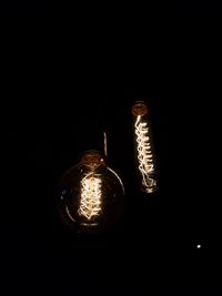 Low angle view of illuminated light bulb against black background