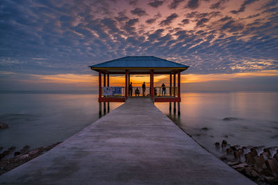 Gazebo on pier by sea against sky during sunset