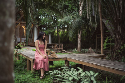 Woman sitting on bench against trees