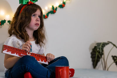 Sad girl celebrates christmas while sitting on the bed.