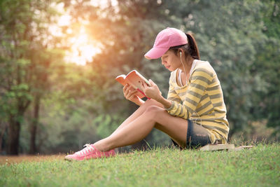 Young woman using phone while sitting on grass