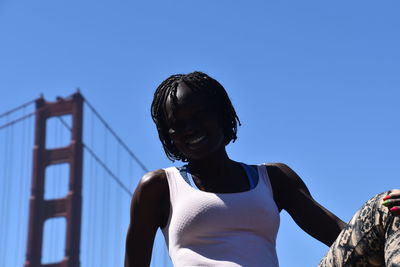 Low angle view of woman standing against clear blue sky