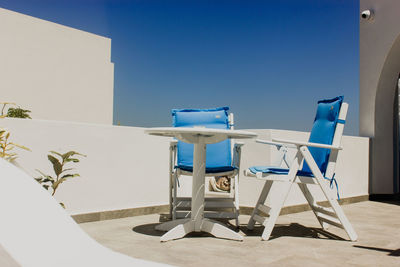 Empty chairs and tables against clear blue sky