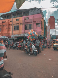 People riding motorcycle on road against buildings