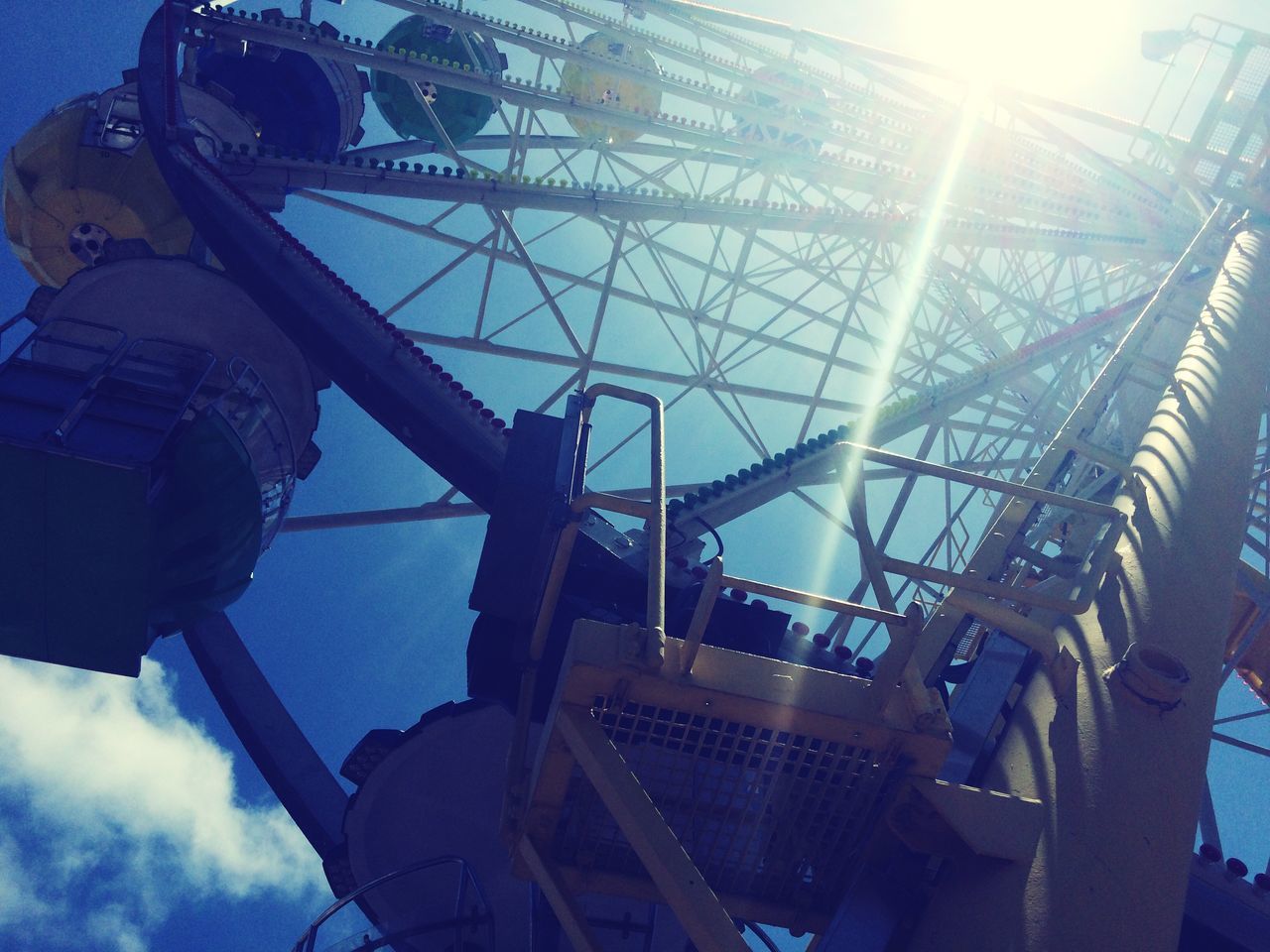 low angle view, sky, built structure, sun, architecture, sunlight, sunbeam, lens flare, building exterior, metal, amusement park ride, cloud - sky, construction site, ferris wheel, amusement park, industry, outdoors, day, blue, no people